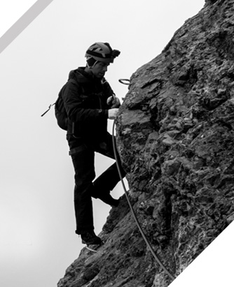 Man In Climbing Gear On Side Of Rock Face