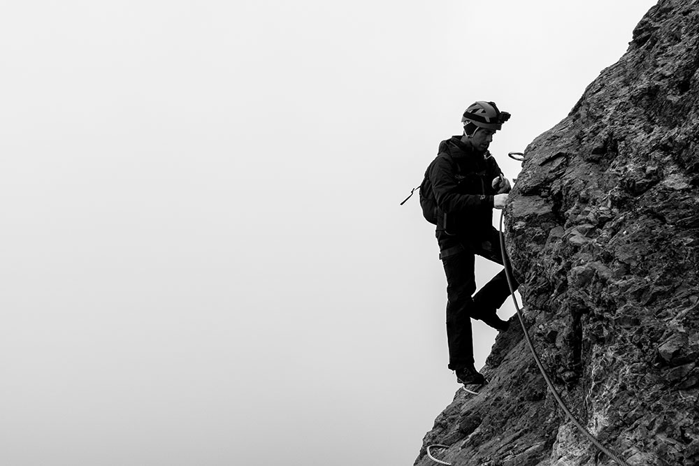 Man In Climbing Gear On Side Of Rock Face